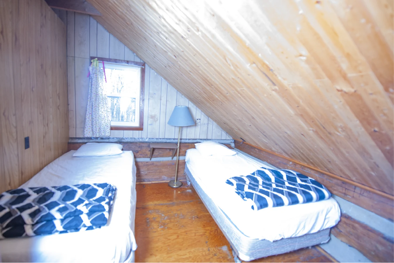 Pigeon Lake Resort Cottage Seven.&nbsp; Upstairs bedroom with two single beds and sloped wooden ceiling in a cottage.